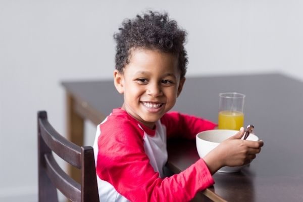 child eating breakfast following his kids morning routine list for kids