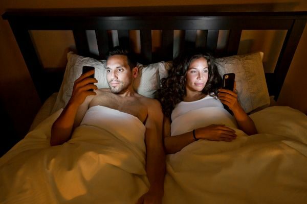 couple looking at phones in bed; no social media challenge