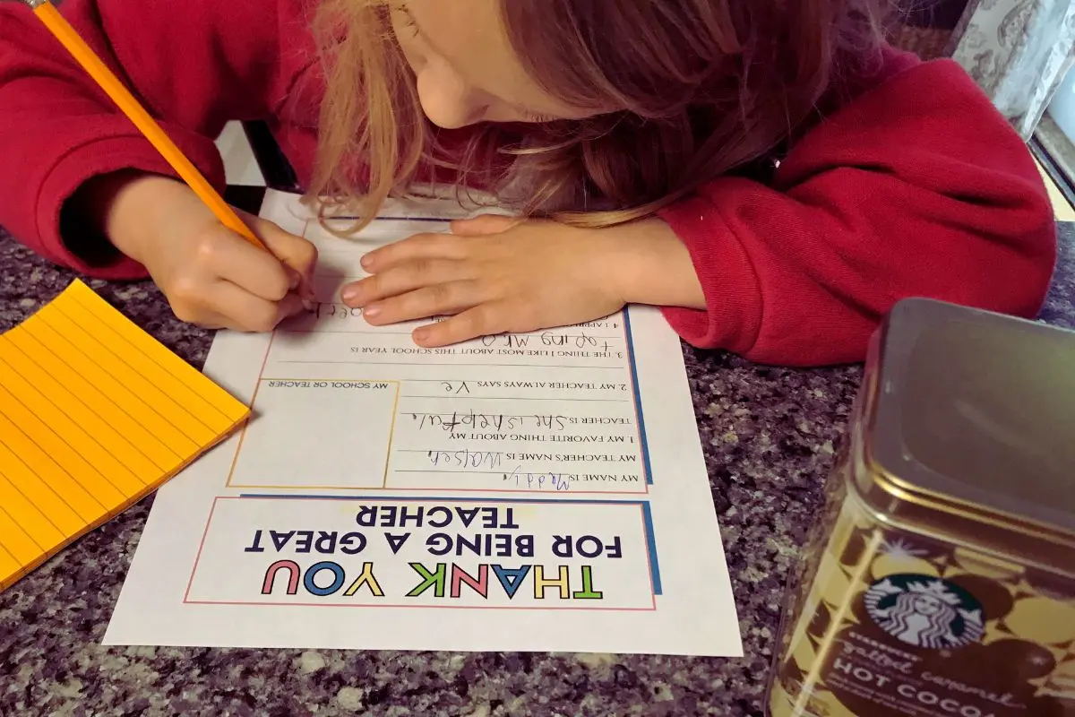 girl completing the thank you card for teacher