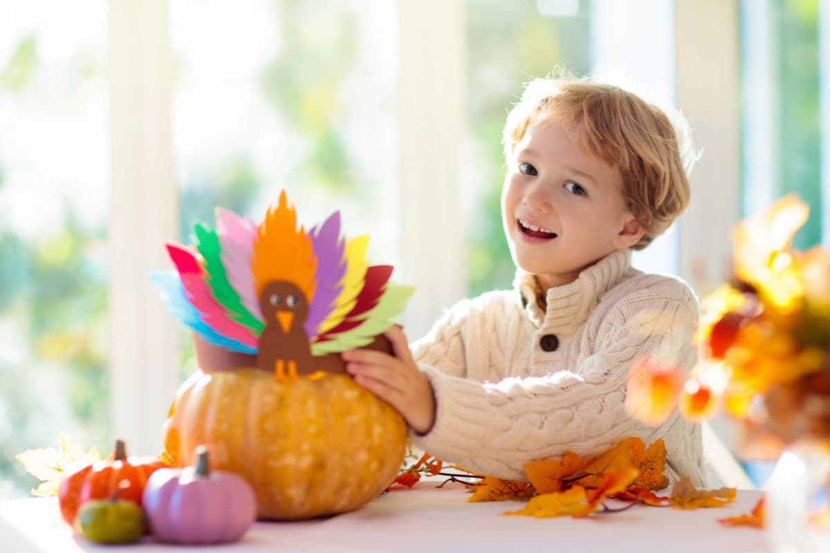 child with pumpkin and homemade turkey craft