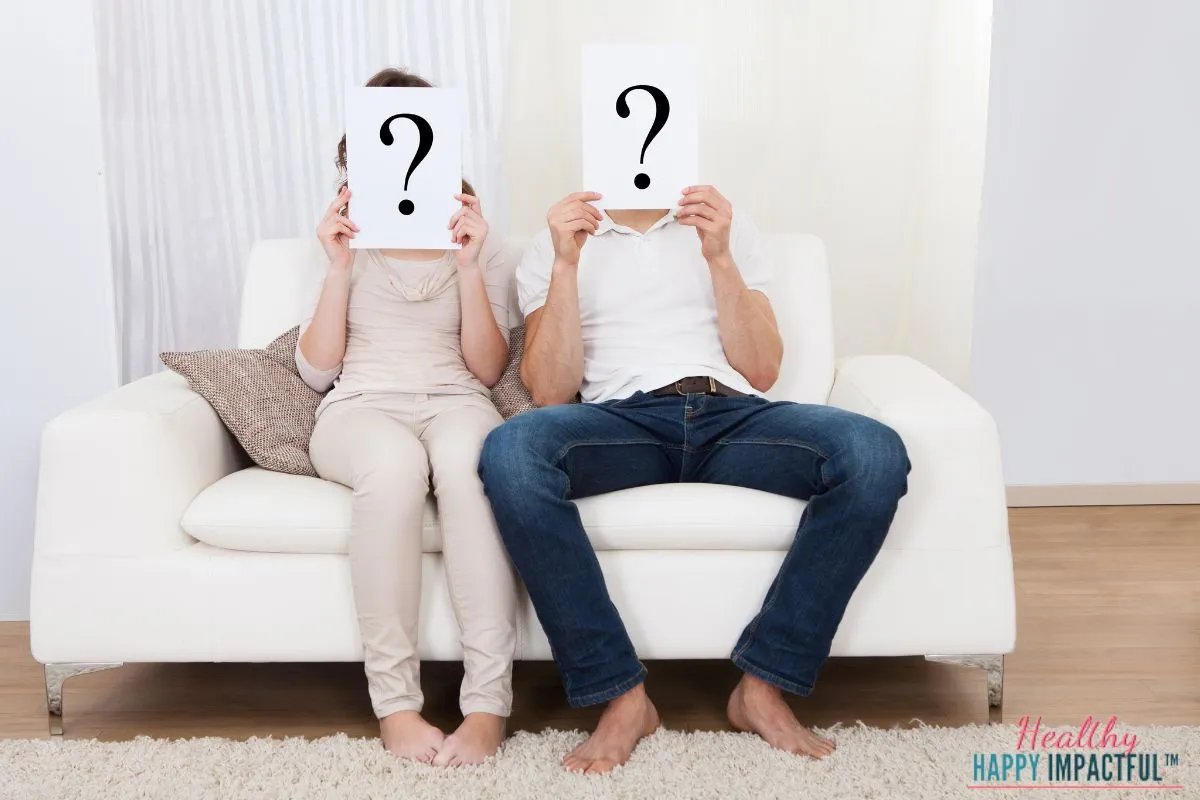 couple sitting on couch holding up question marks