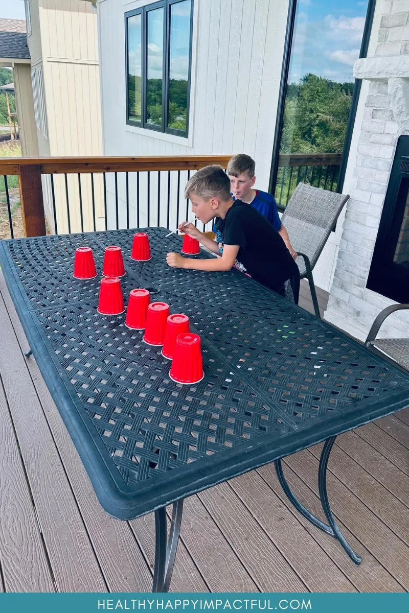 boys blowing cups across the table with straws