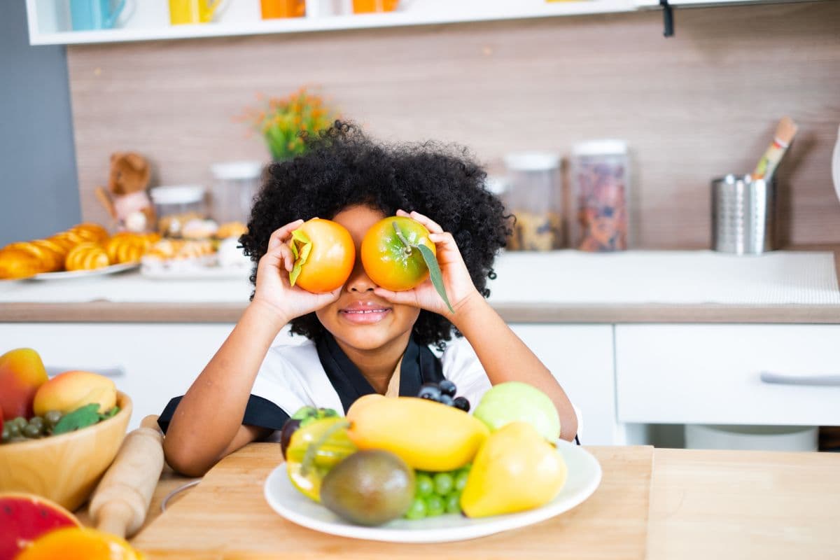 kid holding fruit in front of his eyes