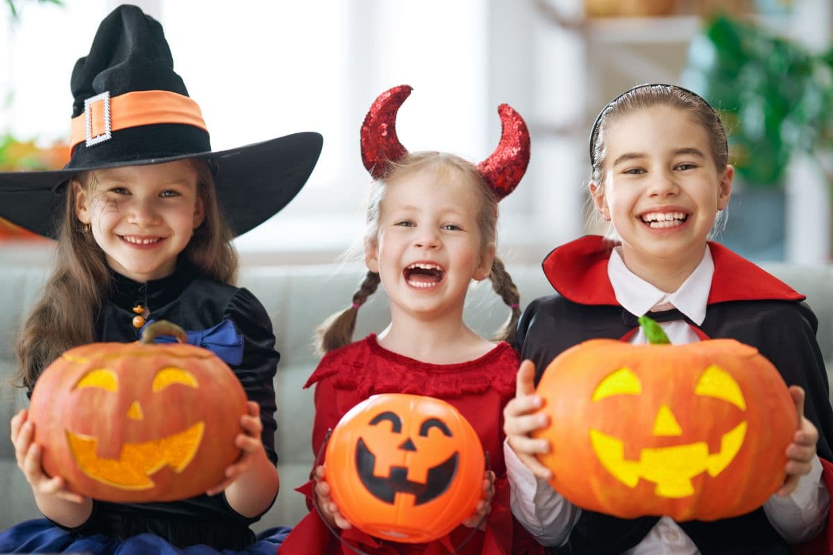 kids holding pumpkins and dressed in costumes