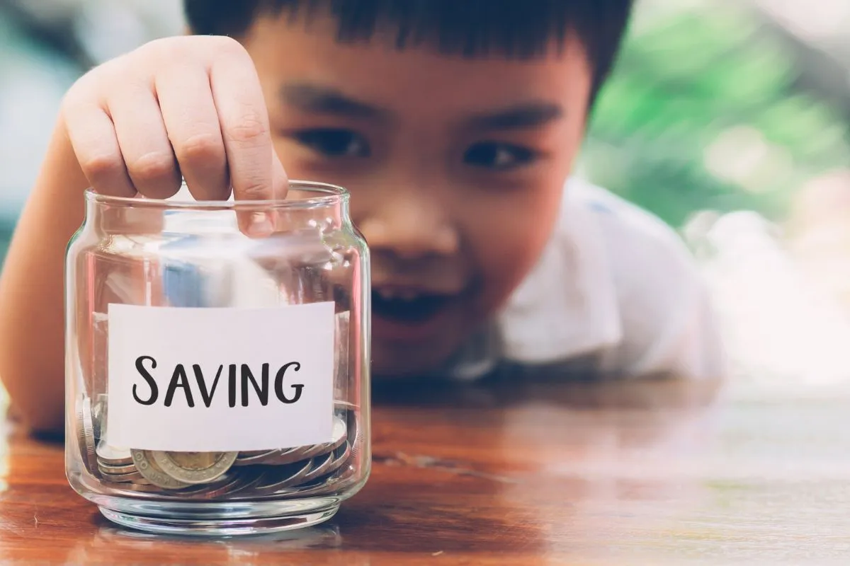 boy putting money in a saving jar