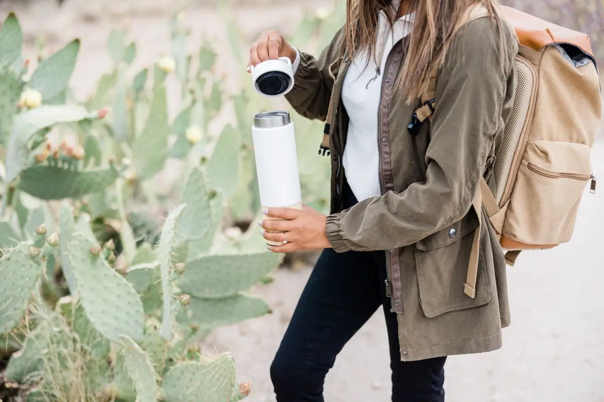 woman holding a cup near a cactus