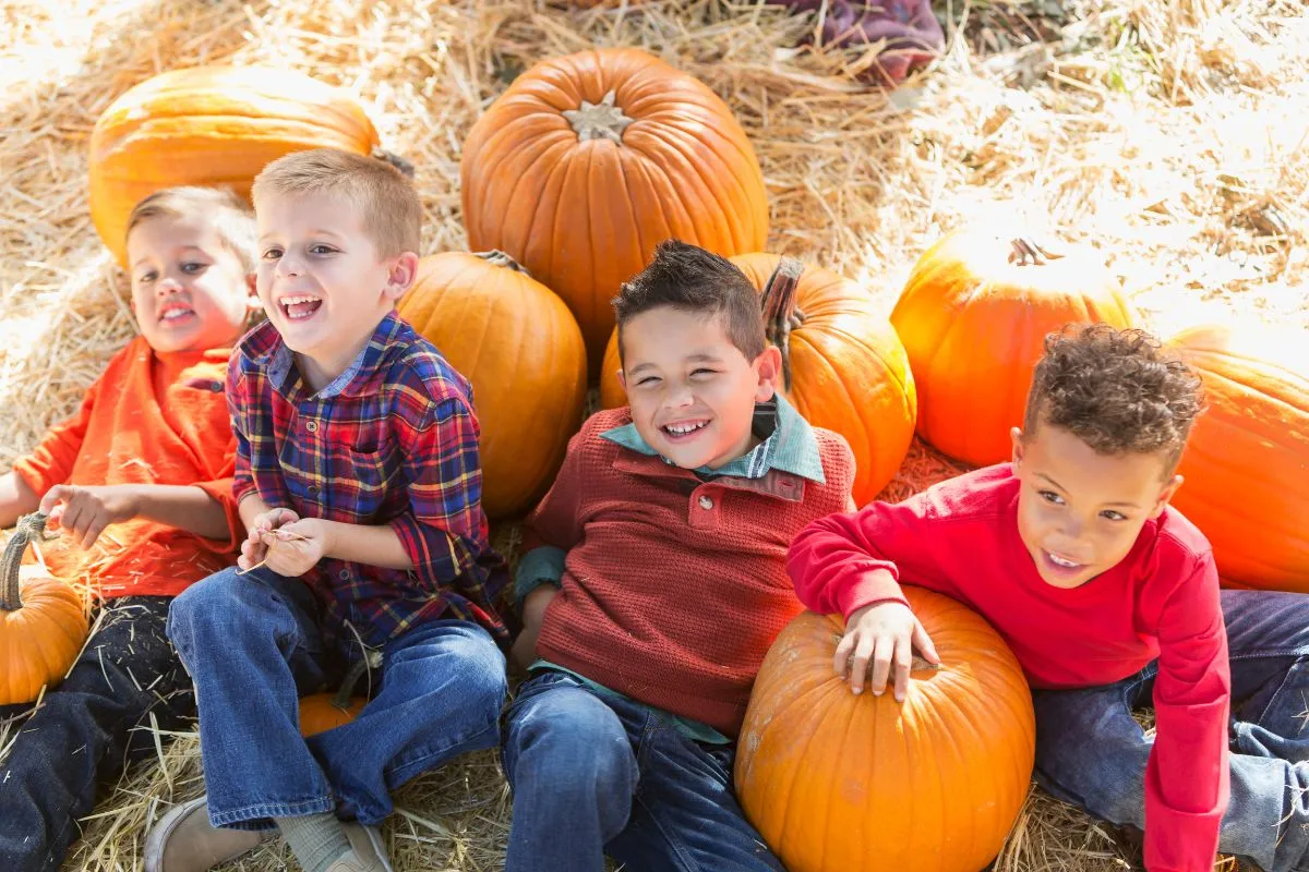 kids laying on pumpkins and hay